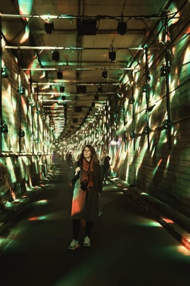 A woman standing in a mirrored corridor of light