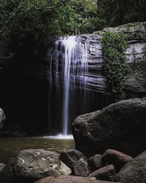 A waterfall dropping into a dark rock pool